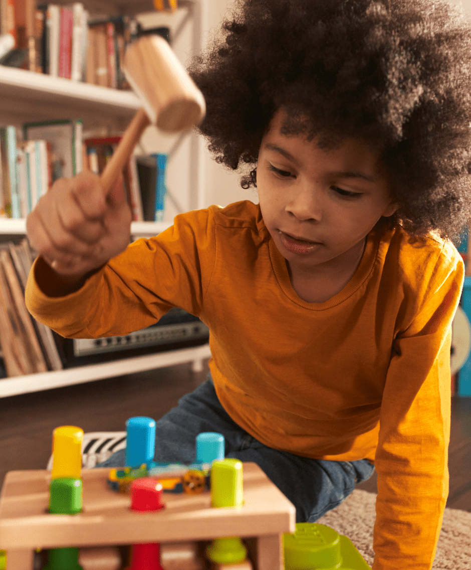 African-American boy playing with a wooden hammer & peg toy